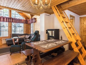 Interior acogedor de una cabaña con una mesa de comedor de madera, un sofá y una chimenea.