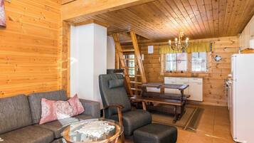 Un interior acogedor de cabaña con sofá, sillón y mesa de comedor.