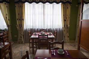 A dining area with a table set for four, chairs, and a window with sheer curtains. - Hotel Castilla (Cáceres)