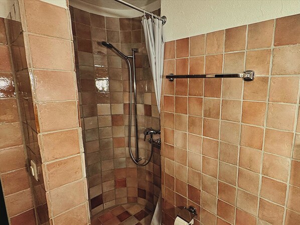 Une douche avec une porte en verre, un porte-serviettes et un mur carrelé.