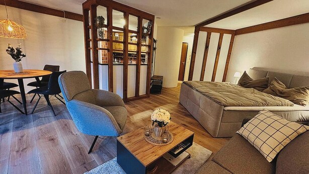 Una sala de estar moderna con un sofá, una mesa de comedor con sillas, una estantería y un jarrón decorativo.