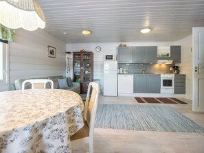 A compact kitchen with modern appliances, a dining area with a table and chairs, and a living space with a sofa and a lamp. - Lehtikuusenranta by Interhome (Rautalampi)