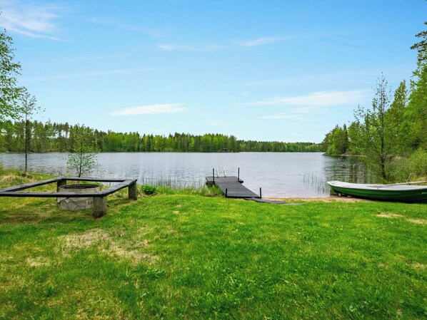 A lakeside view with a dock, a boat, and a picnic table. - Lehtikuusenranta by Interhome (Rautalampi)
