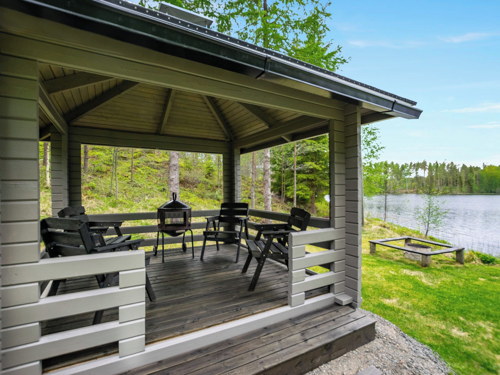 A covered outdoor seating area with a view of a lake and forest.