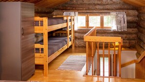 A log cabin with bunk beds, a wooden staircase, and a large wardrobe.