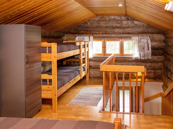 A log cabin with bunk beds, a wooden staircase, and a large wardrobe.
