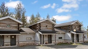 A row of log cabins with a gravel driveway and a clear sky.