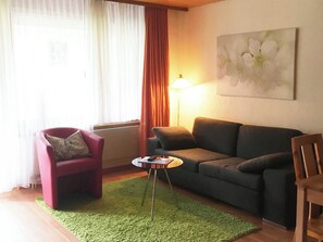 A living room with a red armchair, a grey sofa, a small round table, and a lamp. - Blumenweg 8 Appartement/Fewo 2-Bettwohnung by Interhome (Engelberg)