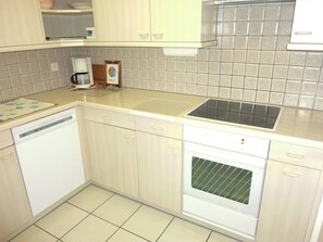 A kitchen with a dishwasher, oven, sink, and a coffee maker on the countertop. - Blumenweg 8 Appartement/Fewo 2-Bettwohnung by Interhome (Engelberg)