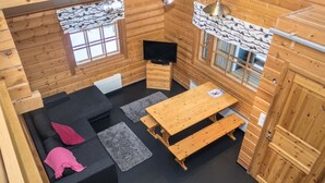 A log cabin interior with a sofa, a wooden table, and a television.