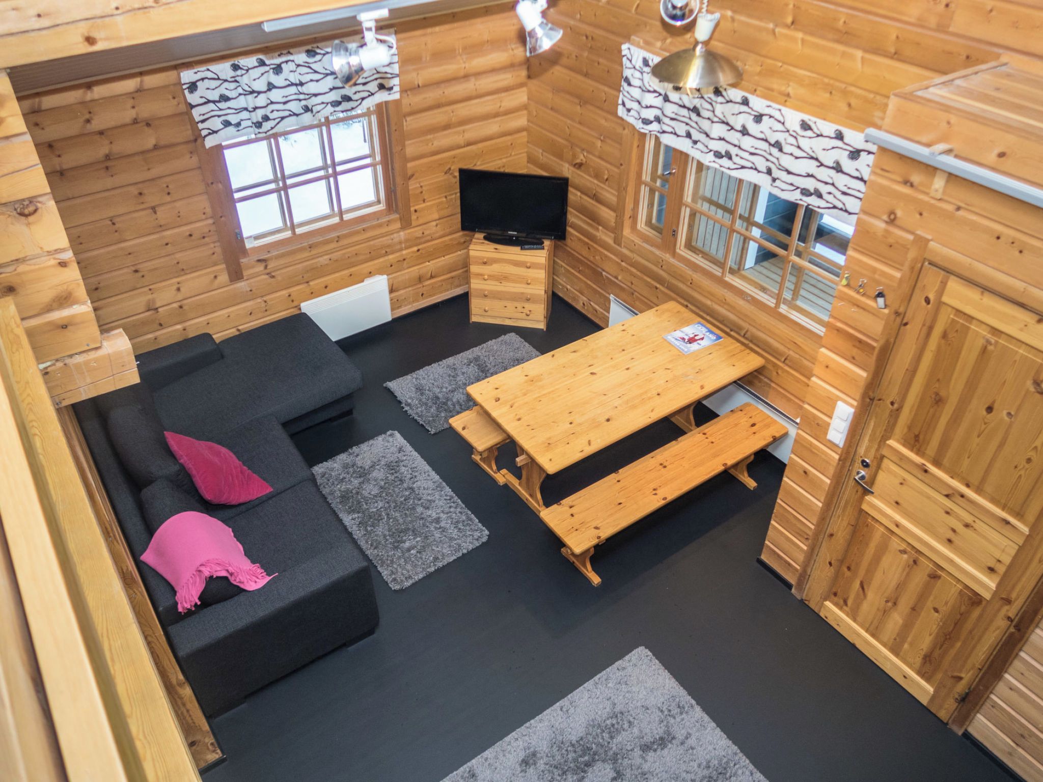 A cozy cabin interior with a sofa, a wooden table, and a television.