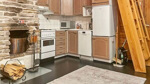 A kitchen with stone walls, wooden cabinets, a stove, a microwave, and a dishwasher.