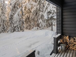 Een houten terras met een metalen emmer en een stapel hout.