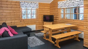 A cozy cabin interior with a sofa, a wooden table, and benches.