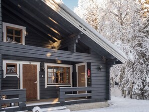 Een chalet met twee verdiepingen, een voortuin, houten deuren en ramen.