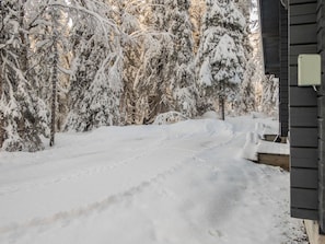 Een sneeuwbedekte pad dat naar een gebouw leidt met een donkere gevel.