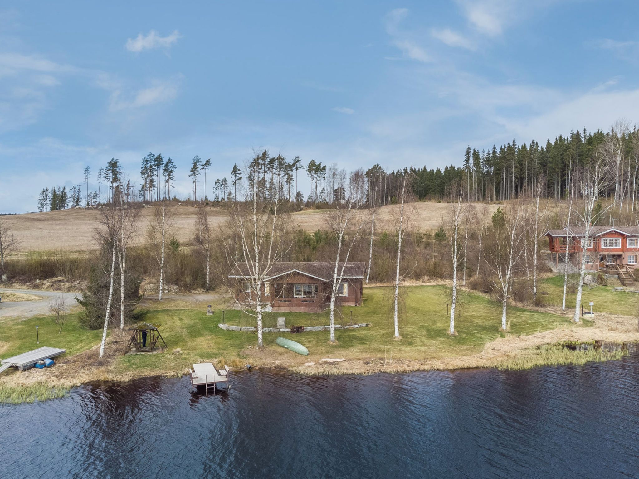 Une propriété au bord du lac, comprenant un chalet en bois, un quai et un bateau.