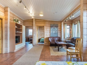 A cozy cabin interior with a wooden interior, a television, a sofa, a dining table, and a chair.