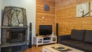 A cozy living room with a stone fireplace, a television, and a sofa. - Tintintupa by Interhome (Nilsiä)