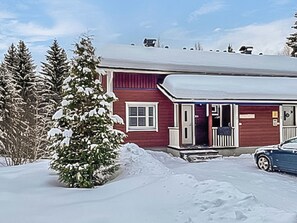A red house with a snow-covered roof, a porch, and a car parked in front. - Tintintupa by Interhome (Nilsiä)