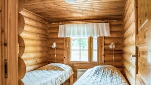Una cabaña con dos literas de madera, una ventana con persianas y una lámpara en el techo.