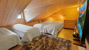 Une chambre confortable située sous les toits, avec deux lits, un plafond en bois et un tableau accroché au mur.