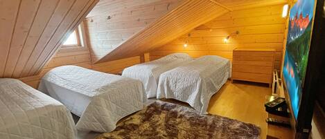 A cozy attic bedroom with two beds, a wooden ceiling, and a painting on the wall.