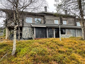 A log cabin with a stone facade, large windows, and a grassy yard.