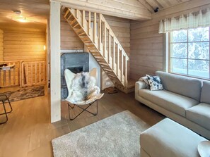 A wooden interior with a staircase, a fireplace, a sofa, and a window. - Alte ruka by Interhome (Kuusamo)