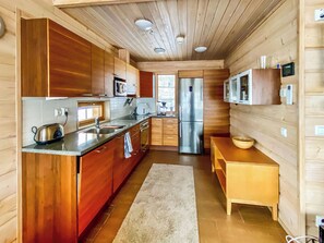 A modern kitchen with wooden cabinets, stainless steel appliances, and a built-in microwave.