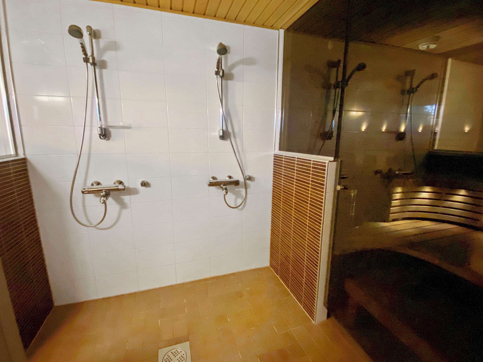 Ein Badezimmer mit zwei Duschkabinen, einer Lüftungsanlage und einem gefliesten Boden.