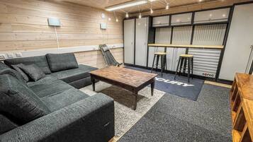 Un espace de détente moderne comprenant un canapé d’angle, une table basse en bois et des tabourets de bar.