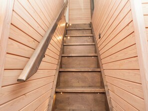 A wooden staircase with a metal handrail leading to a higher level.