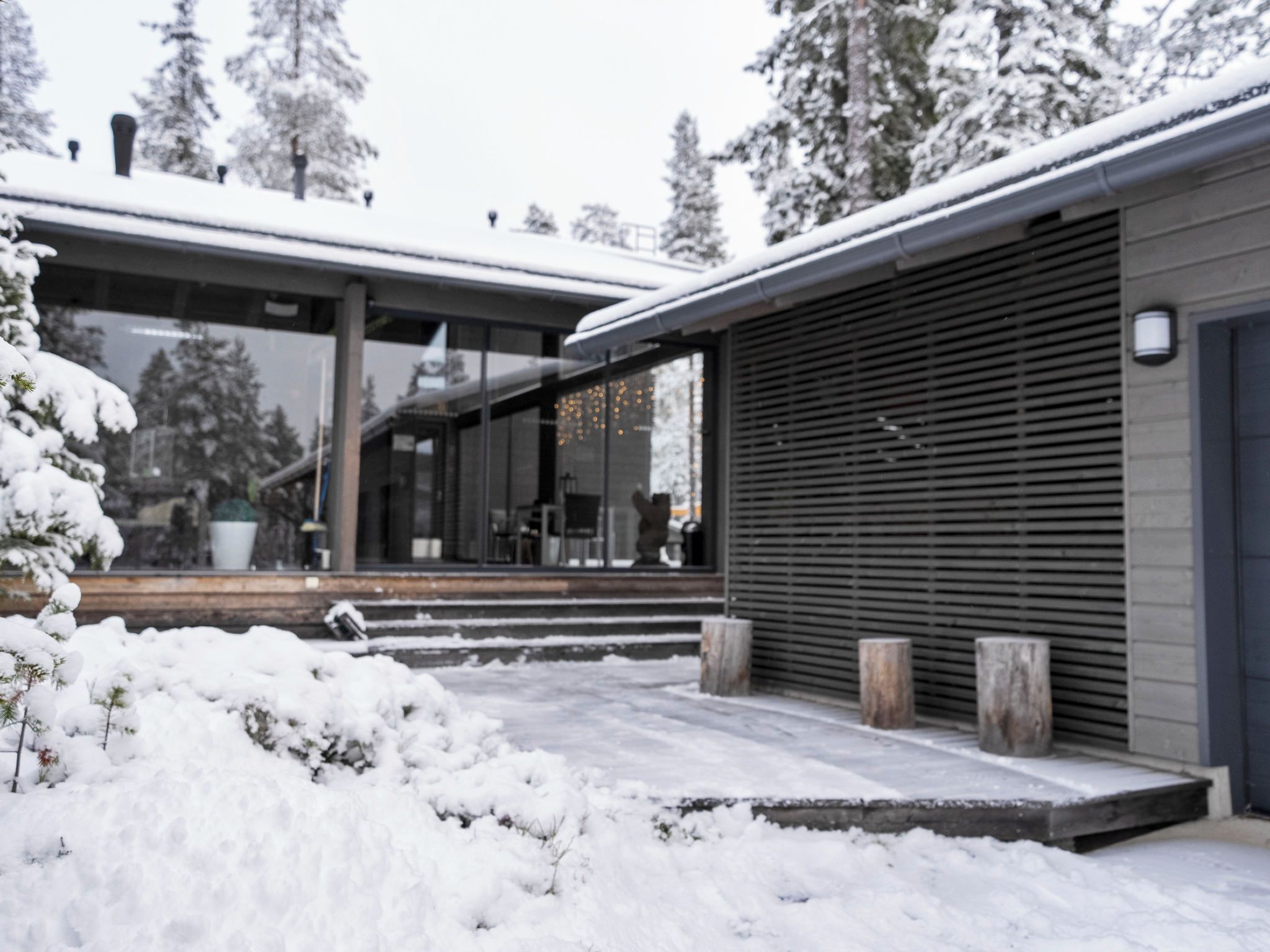 Un edificio moderno con fachada de vidrio, un espacio exterior cubierto y un paisaje cubierto de nieve.
