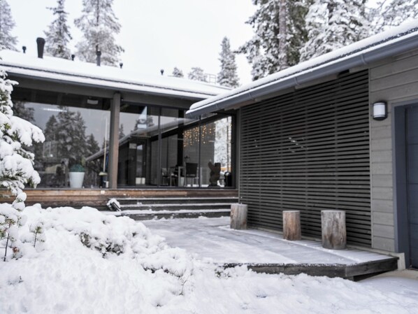 A modern building with a glass facade, a covered outdoor area, and a snow-covered landscape.