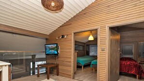 A cozy cabin interior with a TV, a desk, and a bed.