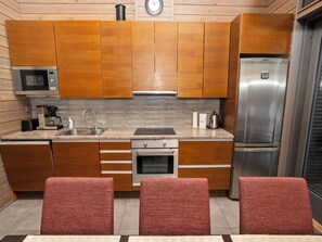 A modern kitchen with wooden cabinets, a stainless steel refrigerator, a microwave, and a built-in oven.