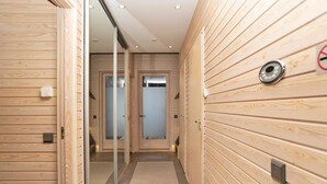 A modern hallway with wooden paneling, a bench, and a door with a frosted glass panel.