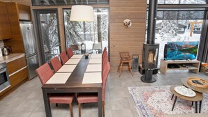 A modern kitchen with a large dining table, a fireplace, and a television.