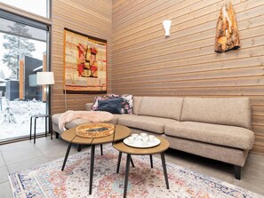 A modern living room with a sofa, two coffee tables, a rug, and a wall tapestry.