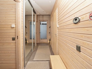 A hallway with wooden paneling, a bench, and a door leading to a room.