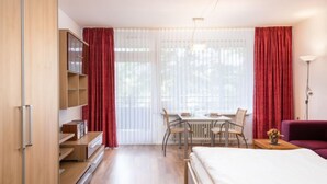 A modern hotel room with a bed, a dining table with chairs, a small table with a vase, and a wardrobe. - Wanderlust (B212) by Interhome (Lahnstein (Koblenz))