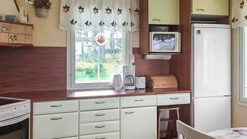 A compact kitchen with a window, a microwave, a refrigerator, and a sink.