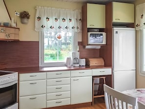 A compact kitchen with a window, a microwave, a refrigerator, and a sink. - Merivanamo by Interhome (Haukipudas)