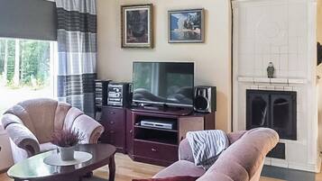 A living room with a sofa, a coffee table, a TV, and a fireplace.
