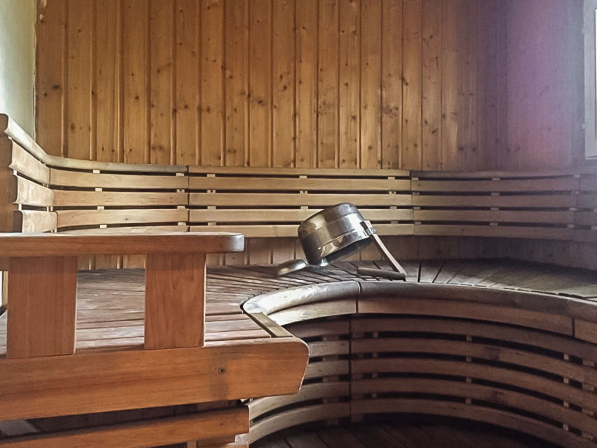 Un sauna avec des bancs en bois et un seau en métal.