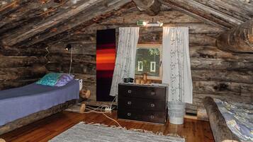 A cozy attic bedroom with a bed, dresser, and a window with curtains.
