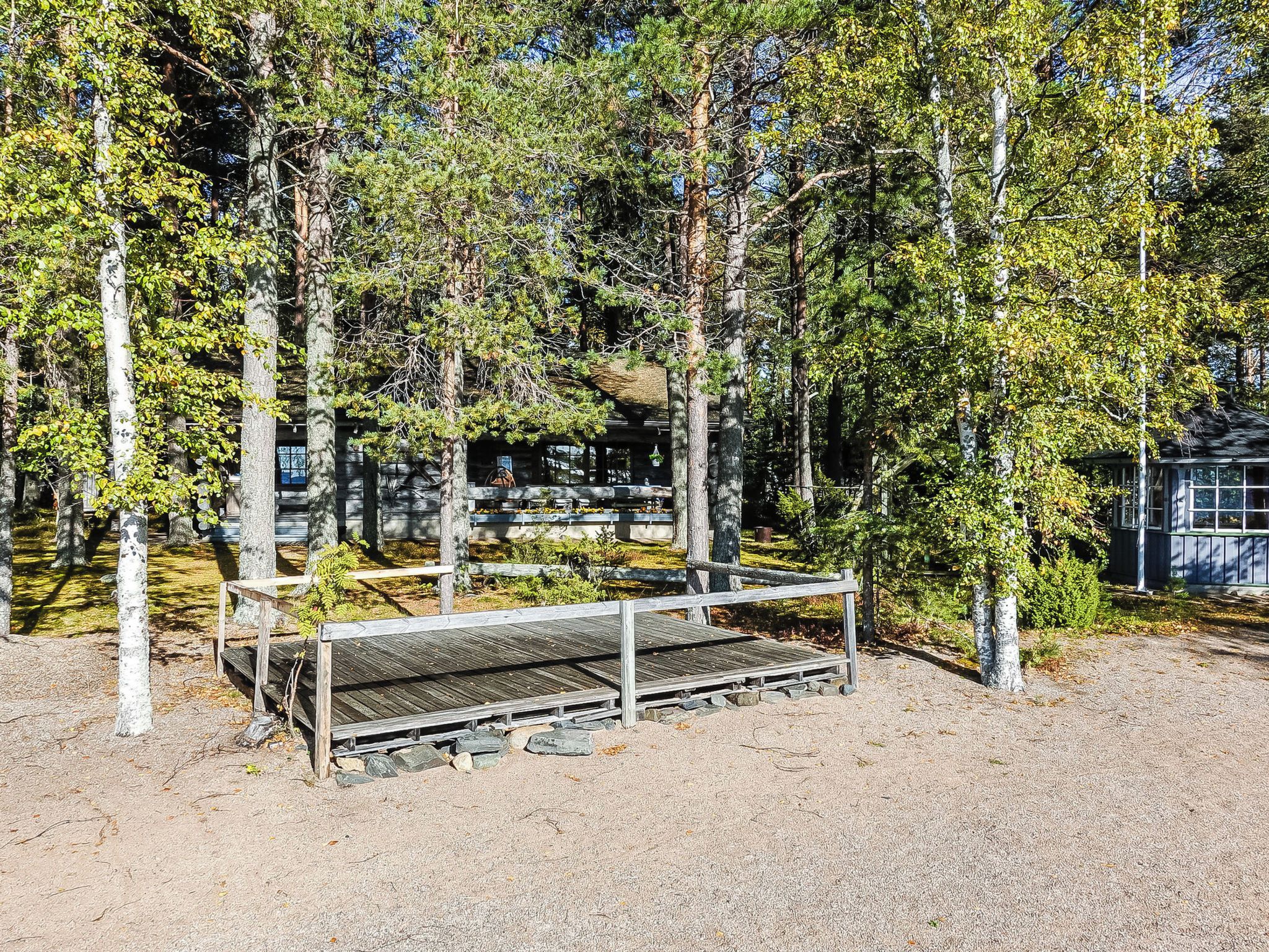 A wooden bench in a forested area with a gravel path.