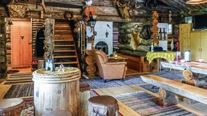 Interior rústico de una cabaña con una escalera de madera, una chimenea y varios trofeos de caza exhibidos en las paredes.