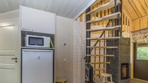 A compact living space with a built-in refrigerator, a small seating area, a fireplace, and a wooden staircase. - Kantapää d2 by Interhome (Sodankylä)